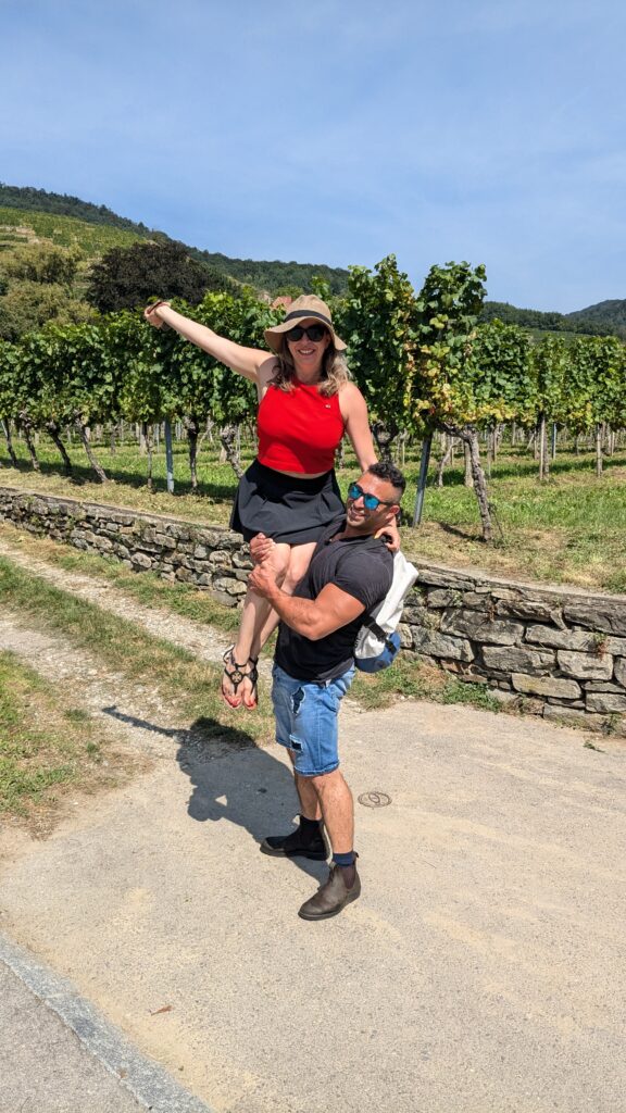 a man carrying a woman in front of stone terraced vineayrds in the wachau valley near spitz